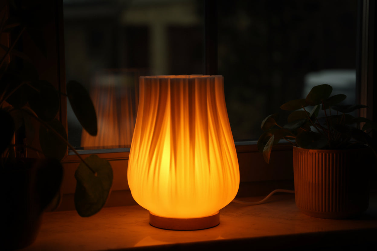 Moonou Cora Tischlampe mit warmem Licht auf der Fensterbank umgeben von Zimmerpflanzen